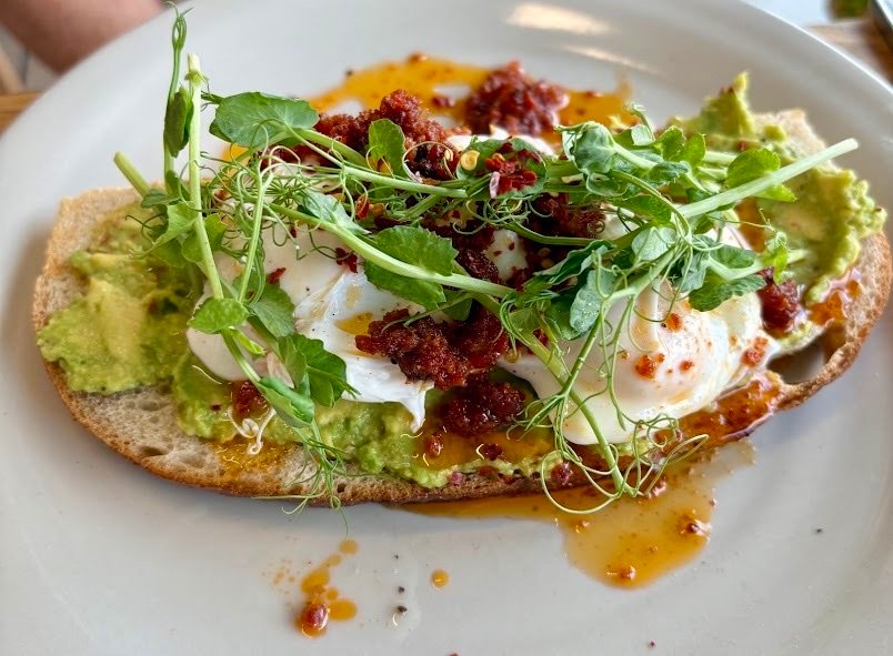 Smashed avocado on toast with poached eggs, chilli and pea shoots