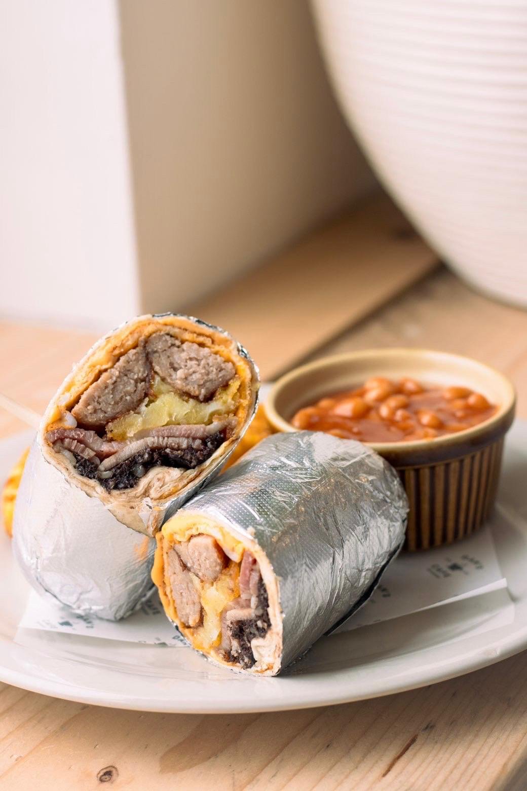Breakfast burrito cut in half, served with beans on a plate