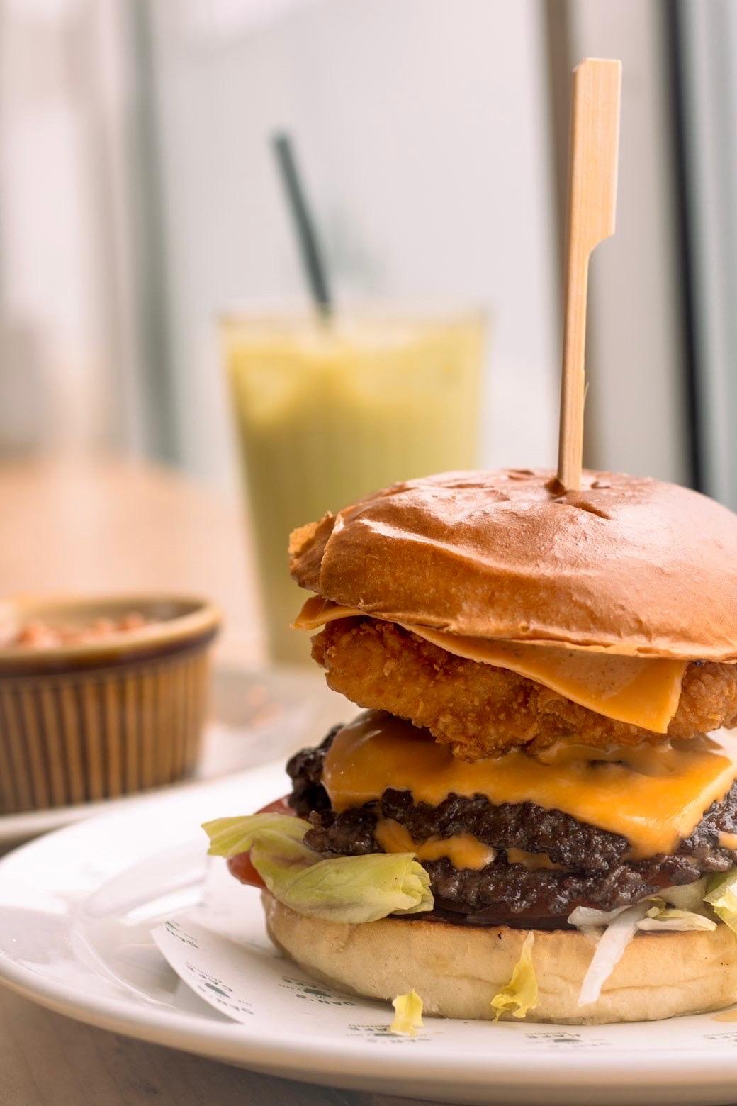 A stacked cheeseburger with crispy chicken, served on a plate
