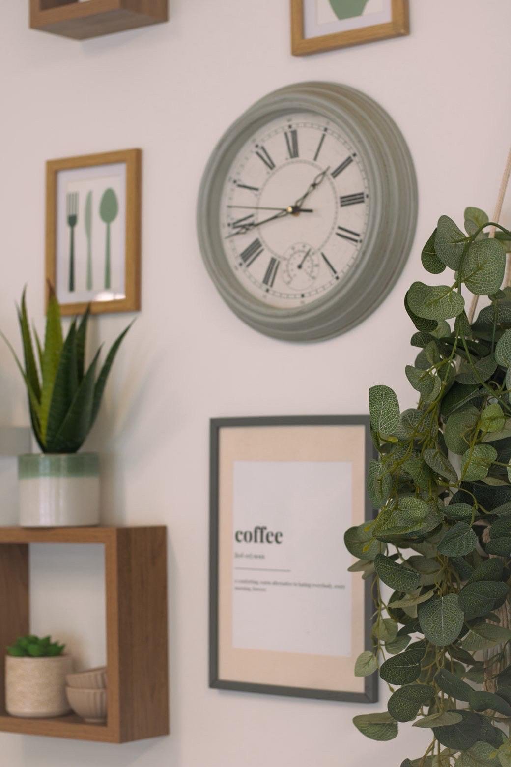 Shelves with plants, prints and a sage green clock on the cafe wall