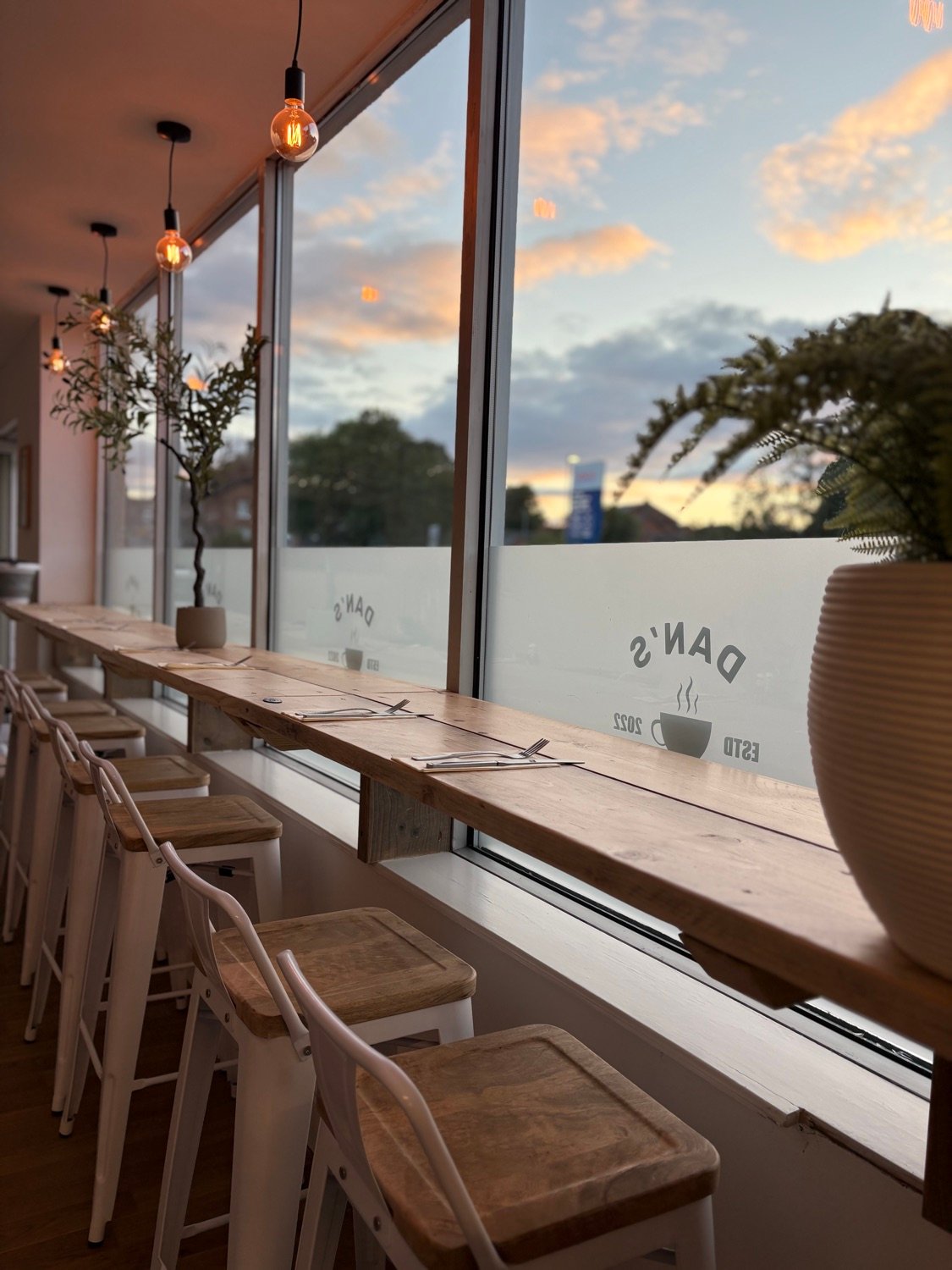 Window bar seating at Dan's Cafe at sunset, with warm pendant bulbs