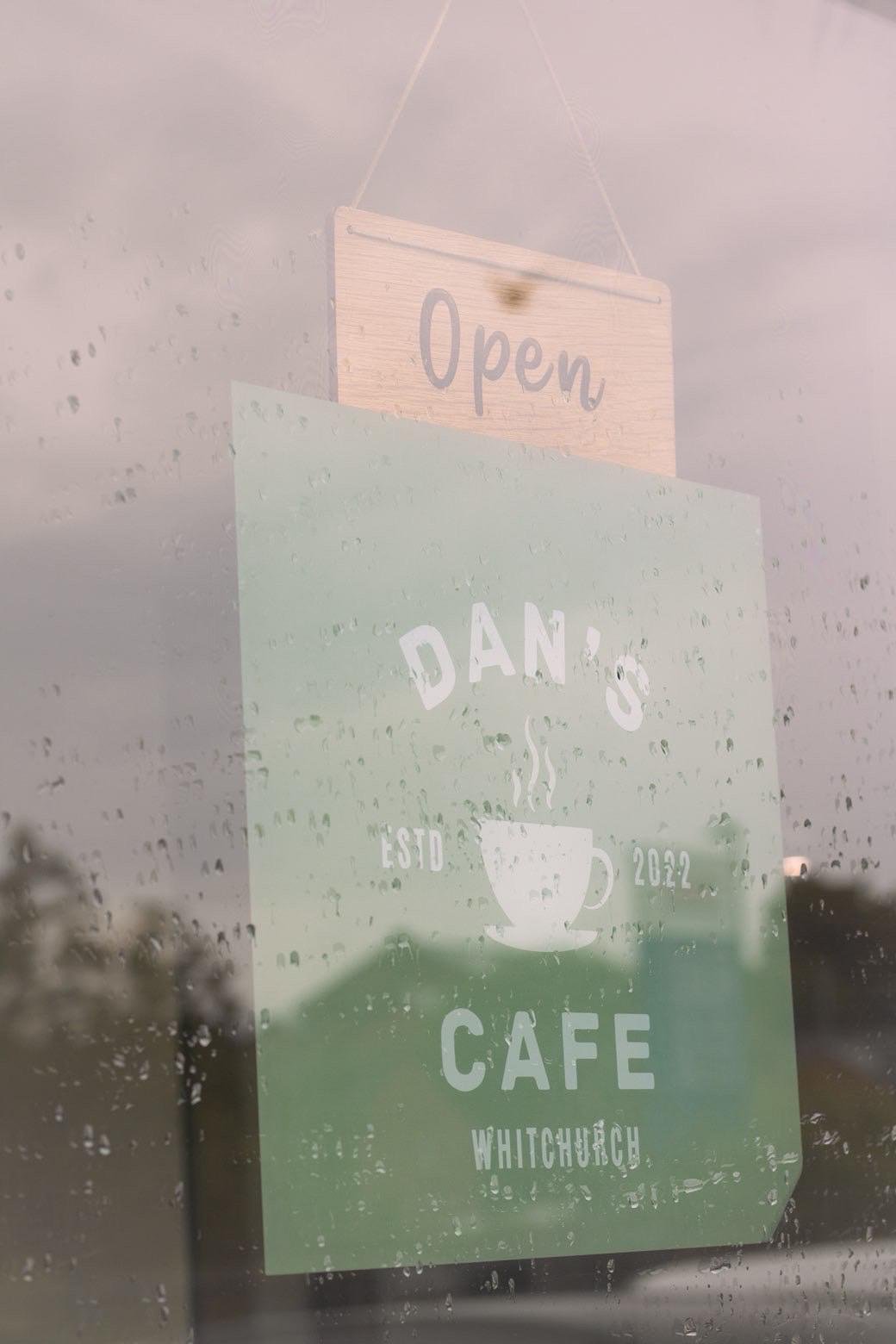 Dan's Cafe window sign and Open sign seen through rain-flecked glass